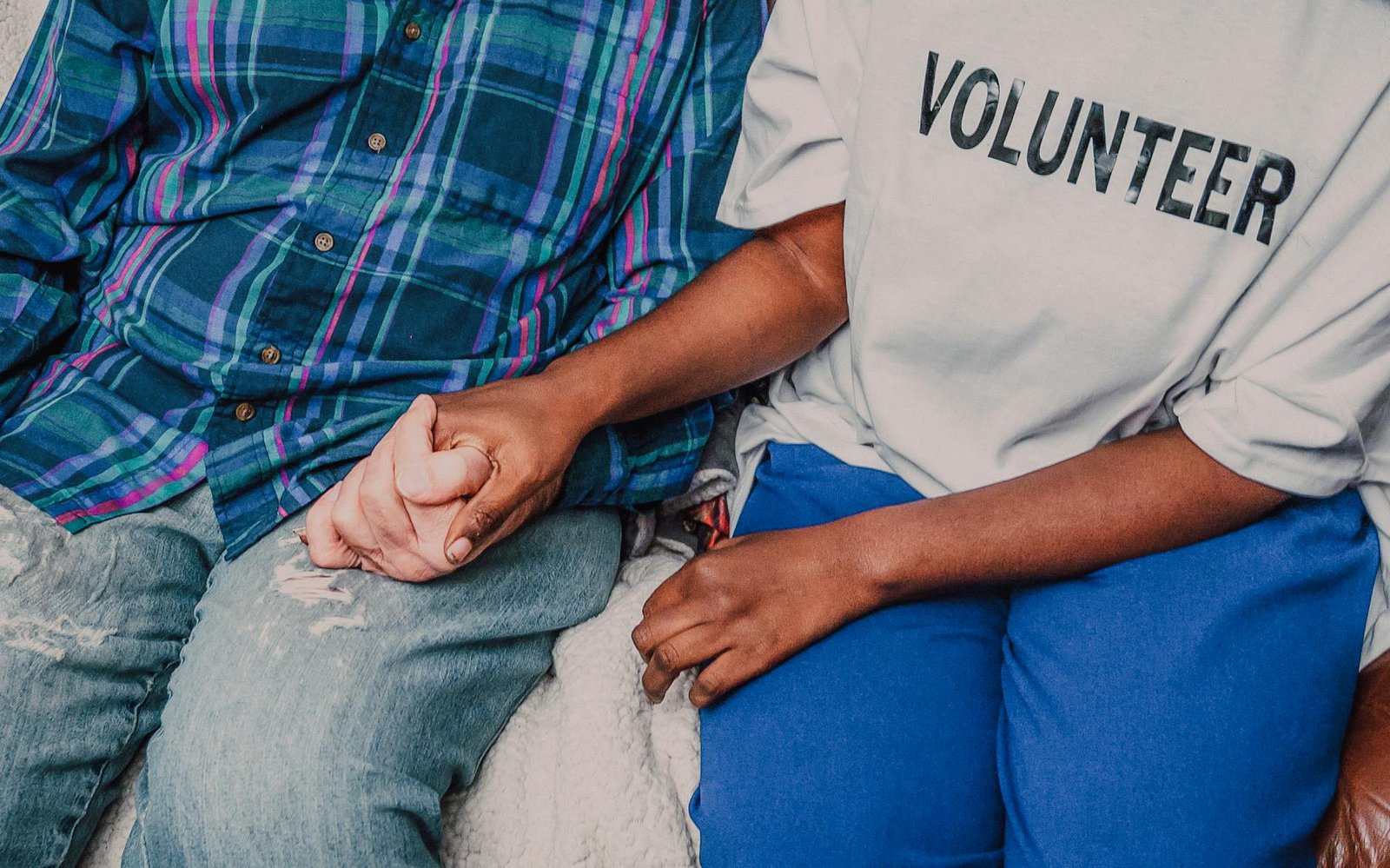Volunteer holding hands with an elderly person in a caring gesture